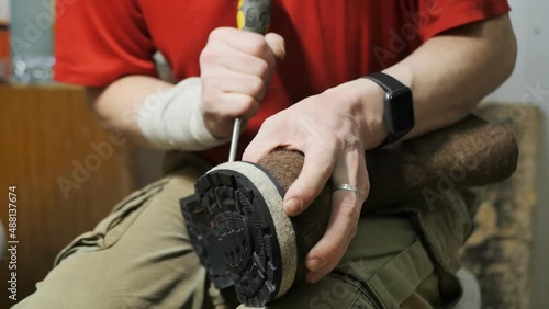 a shoemaker repairs winter insulated high boots made of thick felt while sitting on a chair. Repair of clothes and shoes photo