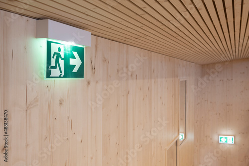 Fototapeta Naklejka Na Ścianę i Meble -  green illuminated emergency lights show way for escape direction in a modern wooden building