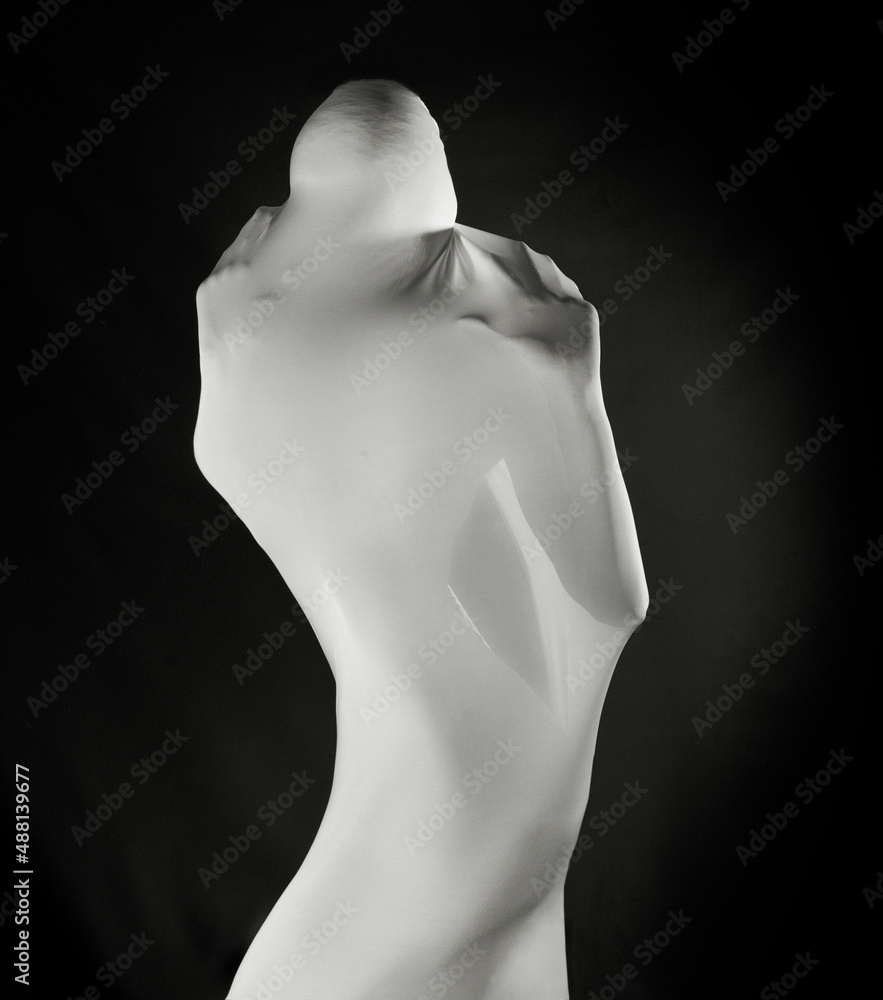 Figure of woman closed with drapery. Woman body isolated in black