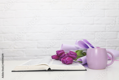 Bible with coffee cup and flowers on white table, christian background with copy space