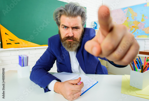 Canvas Print Serious teacher in classroom pointing finger