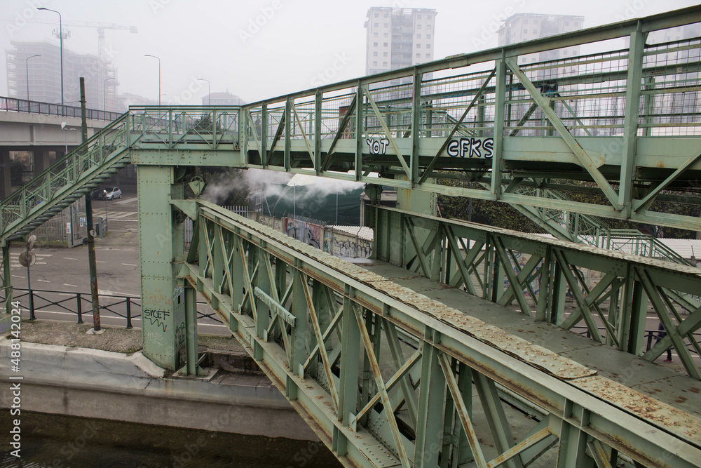 Fototapeta premium Milan, Don Lorenzo Milani overpass, evocative image of the iron bridge along the Naviglio used to connect a ceramic factory with the railway under a gray sky