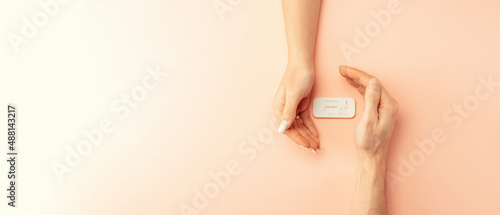 Pregnancy test kit. Female hand hold positive pregnant test with silk ribbon on pink banner background. Medical healthcare gynecological, pregnancy fertility maternity people concept. © Maksym