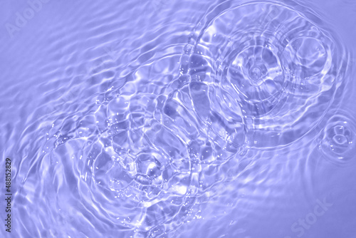 Circles on water. Blue round shadows. Blurred background made with water and light in monochrome. Pureness and freshness concept. Trendy violet color of the year 2022 