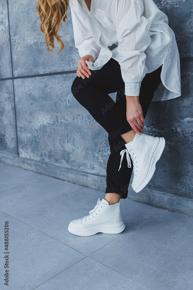 Women's legs in black trousers and white leather sneakers. Modern casual  style. New shoe collection foto de Stock | Adobe Stock