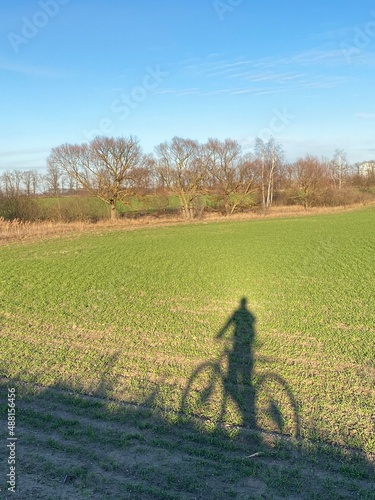 Shadow of a bicyclist on a bike on green grass in the field