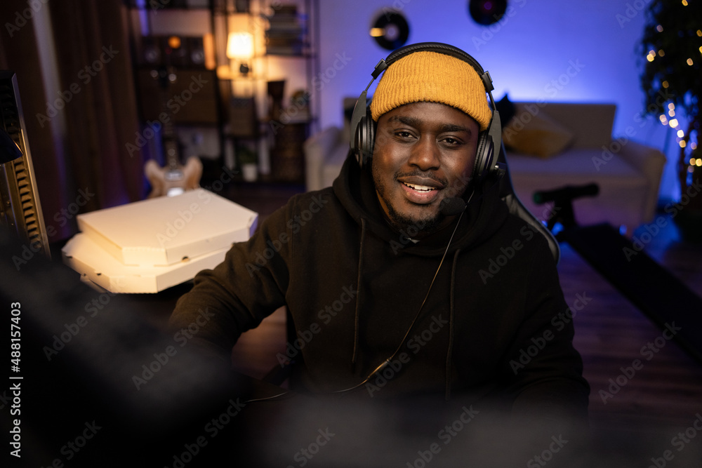 A dark men's room at night illuminated by purple led lights. A guy wearing a cap and headset sits in a comfortable chair in front of a computer, watching videos, browsing the internet A dark men's room at night illuminated by purple led lights. A guy wearing a cap and headset sits in a comfortable chair in front of a computer, watching videos, browsing the internet