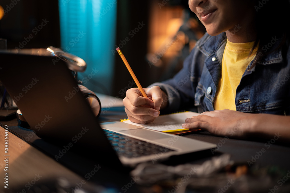 Girl's hands taking notes with pencil in notebook, laptop, headphones, teenage girl has remote lessons, distance learning, online school Girl's hands taking notes with pencil in notebook, laptop, headphones, teenage girl has remote lessons, distance learning, online school