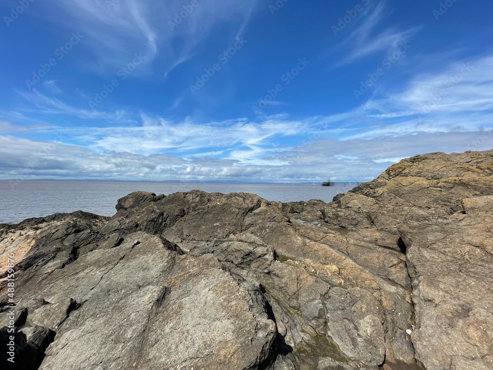 A view of the rocks at the beach leading out to the open muddy water with the beautiful blue sky in the background A view of the rocks at the beach leading out to the open muddy water with the beautiful blue sky in the background