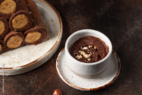 Vegan chocolate hazelnut spread in ceramic bowl on dark background. Healthy vegan food concept. closeup