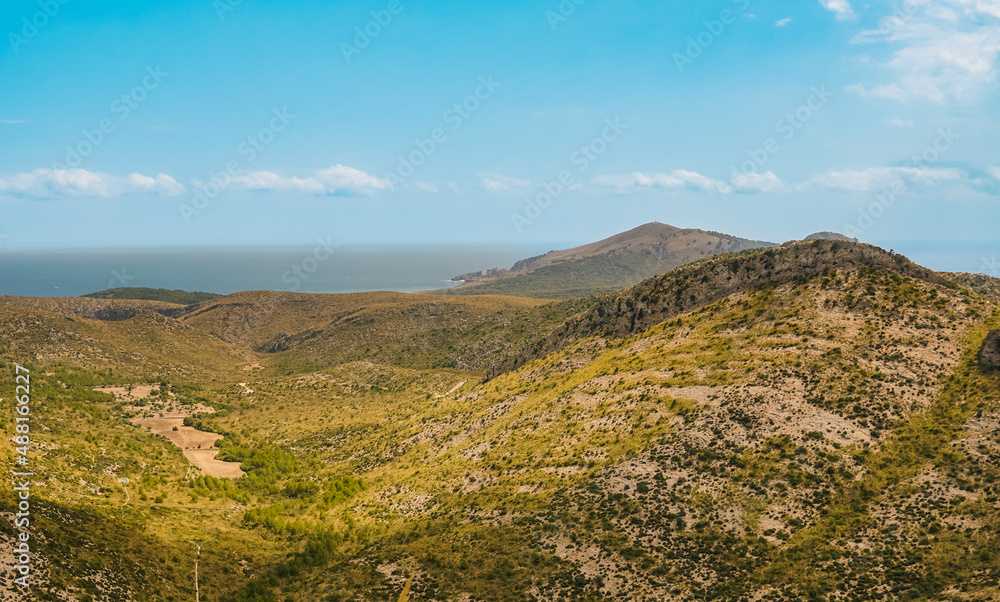 sunny landscape with mountains and sky and blue ocean