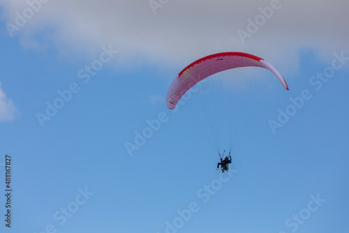 Paragliders in bright blue sky, tandem of instructor and beginner