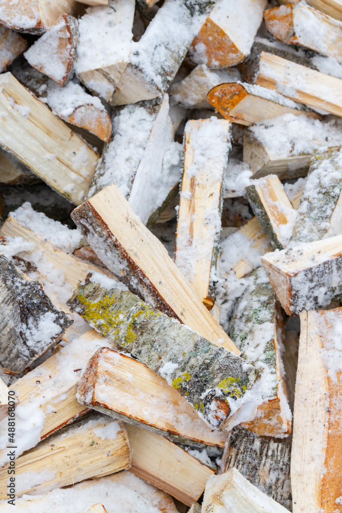 Chopped birch firewood lies in a heap on the snow in winter Chopped birch firewood lies in a heap on the snow in winter