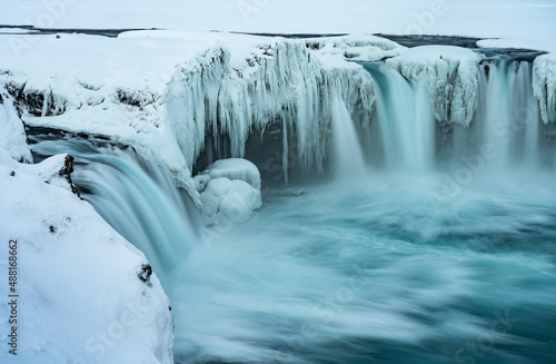 Godafoss Waterfall in Iceland, partially frozen in winter. Long exposure motion blur