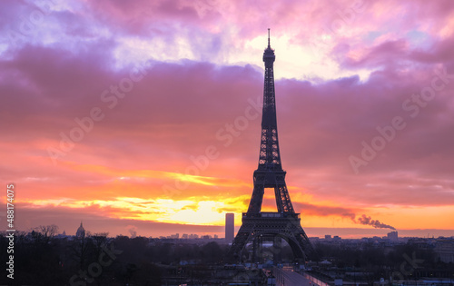 Silhouette of the Eiffel tower with dramatic sky in the background. Orange clouds at sunset or sunrise.