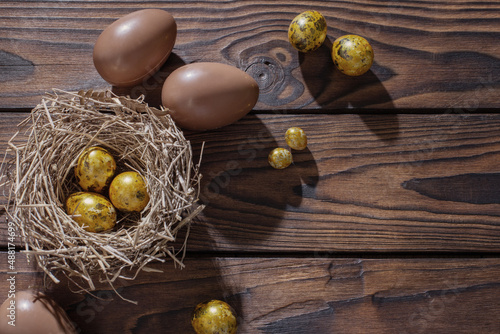 golden and chocolate easter eggs on dark wooden background