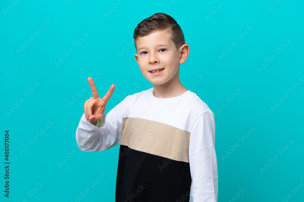 Little kid boy isolated on blue background smiling and showing victory sign Little kid boy isolated on blue background smiling and showing victory sign