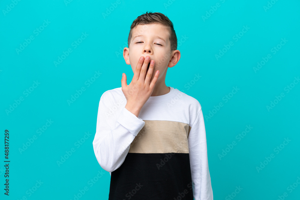 Little kid boy isolated on blue background yawning and covering wide open mouth with hand Little kid boy isolated on blue background yawning and covering wide open mouth with hand