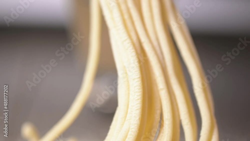 Cooking traditional homemade Italian pasta in kitchen in  restaurant. raw noodles made from dough. close-up preparing homemade handmade spaghetti. Spaghetti production on a noodle machine. pasta maker