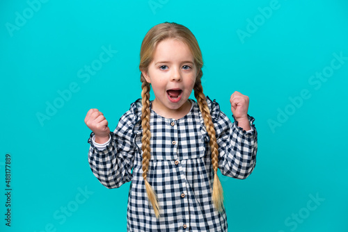 Little caucasian girl isolated on blue background celebrating a victory