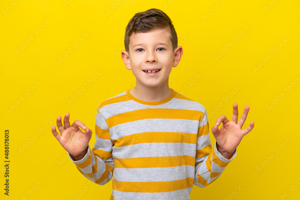 Little caucasian boy isolated on yellow background showing ok sign with two hands Little caucasian boy isolated on yellow background showing ok sign with two hands
