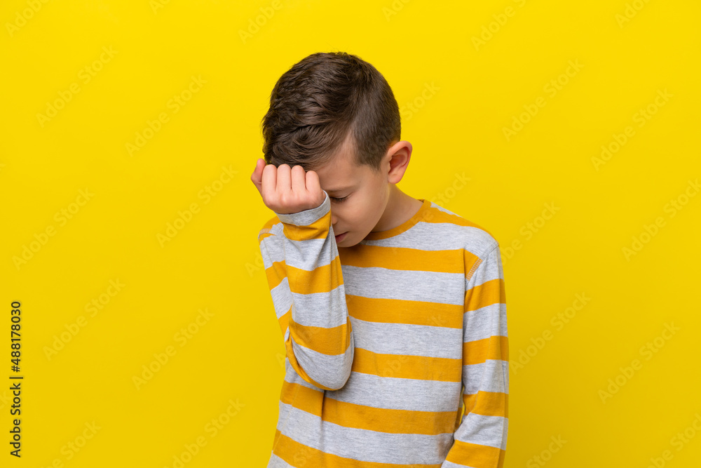 Little caucasian boy isolated on yellow background with headache Little caucasian boy isolated on yellow background with headache