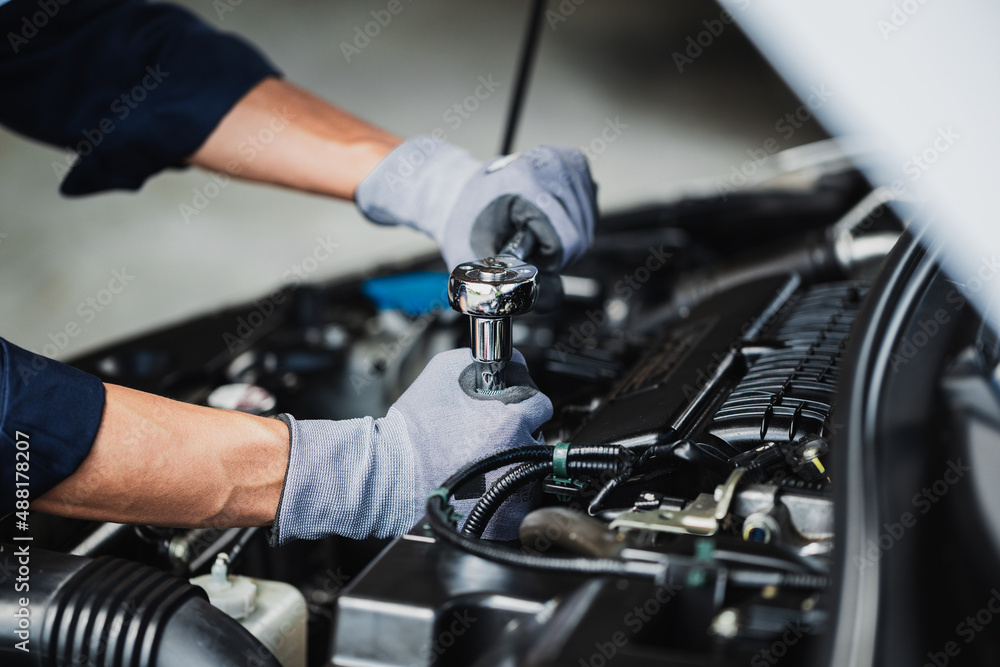 Professional mechanic working on the engine of the car in the garage. Car repair service. Professional mechanic working on the engine of the car in the garage. Car repair service.