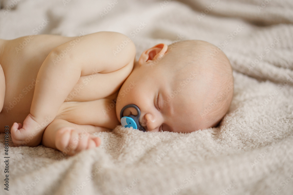 a beautiful naked baby with nipple sleeps on the bed. a beautiful naked baby with nipple sleeps on the bed.