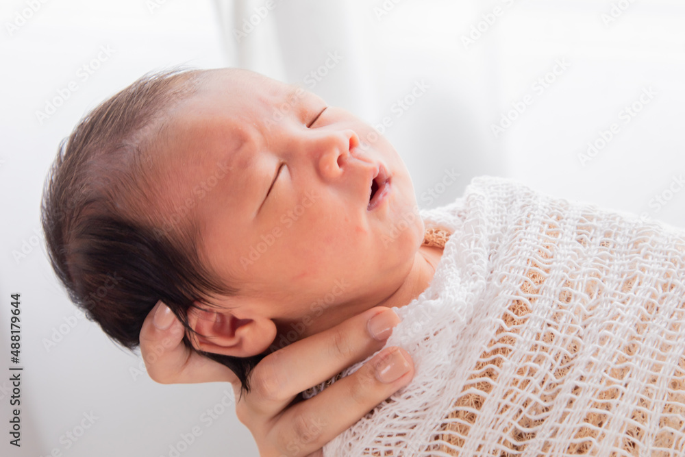 Close up of Asian little baby in arm deeply sleeping with happy and safe. Newborn sleep in mom hand with safe and tender, adorable infant lying wrapped in thin white cloth. Close up of Asian little baby in arm deeply sleeping with happy and safe. Newborn sleep in mom hand with safe and tender, adorable infant lying wrapped in thin white cloth.