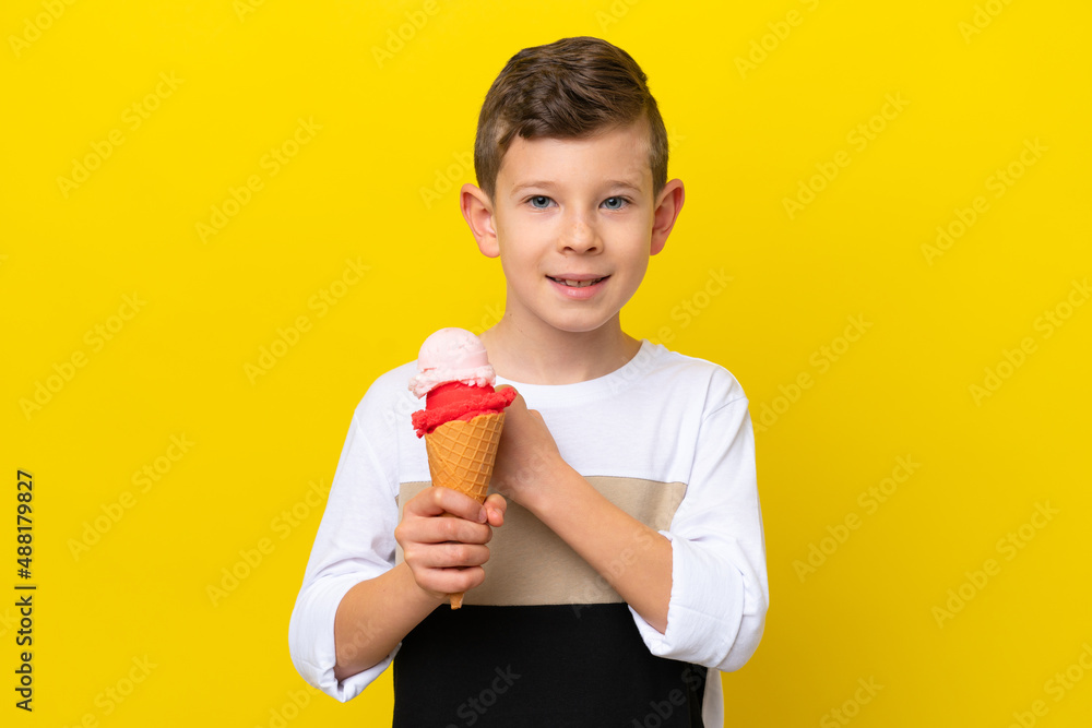 Little caucasian boy with a cornet ice cream isolated on yellow background celebrating a victory Little caucasian boy with a cornet ice cream isolated on yellow background celebrating a victory