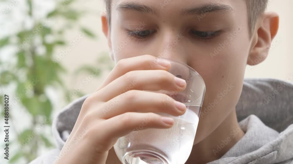 Close up of teenage boy taking vitamin D-3 softgel pill with glass of water. Healthcare and medicine concept. 4K Close up of teenage boy taking vitamin D-3 softgel pill with glass of water. Healthcare and medicine concept. 4K