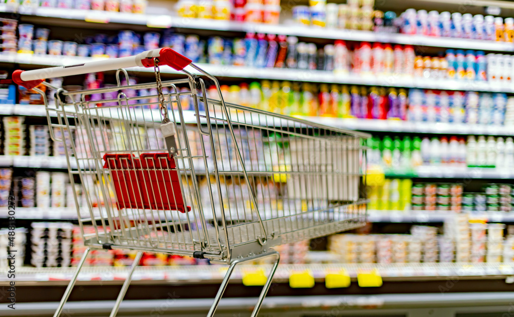A shopping cart by a store shelf in a supermarket