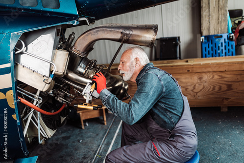 Professional senior helicopter mechanic working in air vehicle repair service.