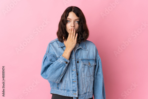 Teenager Ukrainian girl isolated on pink background covering mouth with hand