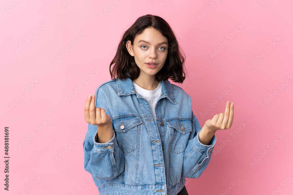 Teenager Ukrainian girl isolated on pink background making money gesture Teenager Ukrainian girl isolated on pink background making money gesture