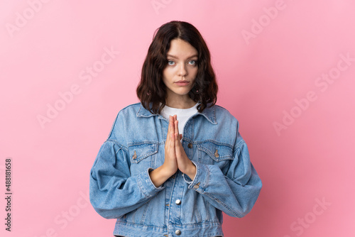 Teenager Ukrainian girl isolated on pink background keeps palm together. Person asks for something © luismolinero