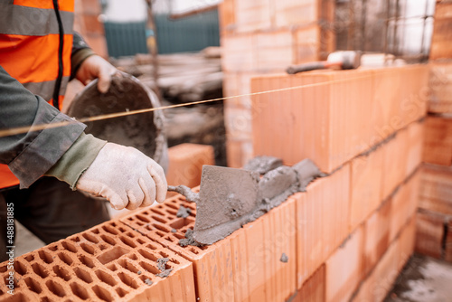 Close up details of industrial bricklayer installing bricks on industrial building, construction site photo