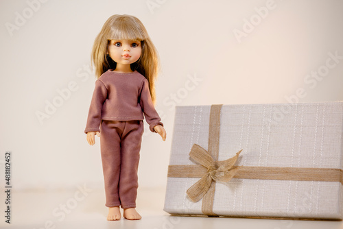 Obraz na płótnie Pretty doll demonstrating her pajamas and standing next to the gift w salonie