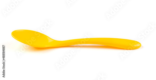 Bright yellow plastic spoon for feeding the baby on a white isolated background. Side view.