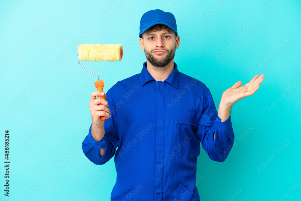 Painter caucasian man isolated on blue background having doubts while raising hands Painter caucasian man isolated on blue background having doubts while raising hands