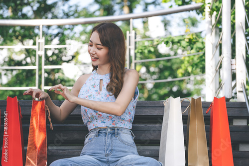 Happy young adult asian woman with shopping bags.