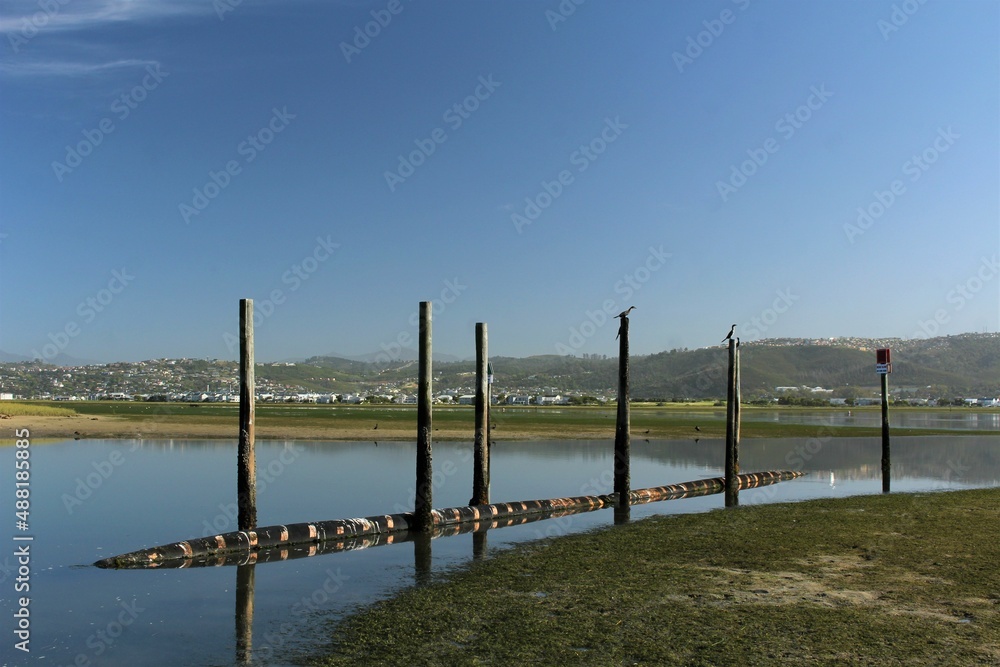 Blue sea and poles reflected on water at Knysna Boat Club