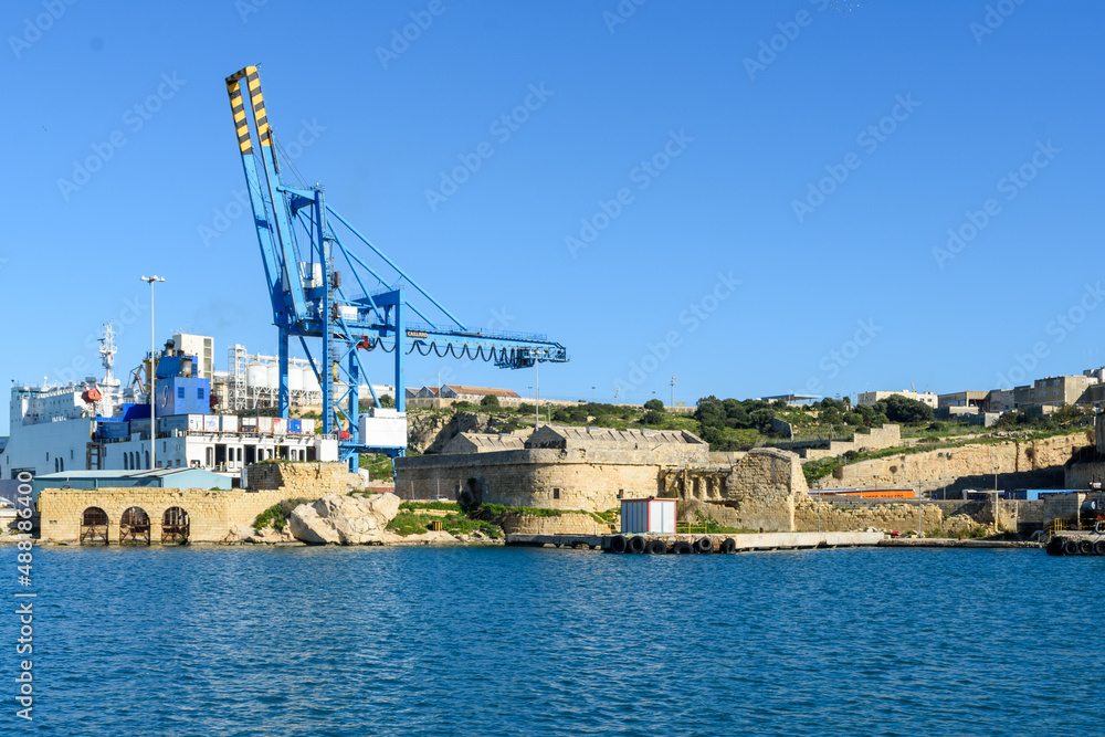 Paola, Malta - Remains of the Corradino Lines fortifications built in the 1870’s and the Ras Ħanżir Polverista (gunpowder store) built in 1756. In the background are cranes at the Paola dockyards.