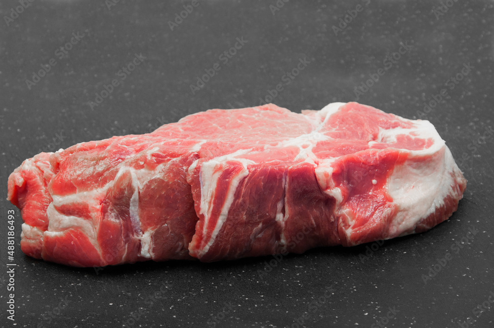 fresh piece of pork meat on a black background. juicy meat for steak on a dark texture. meat processing industry concept. a piece of raw fillet on the countertop. cooking illustration fresh piece of pork meat on a black background. juicy meat for steak on a dark texture. meat processing industry concept. a piece of raw fillet on the countertop. cooking illustration
