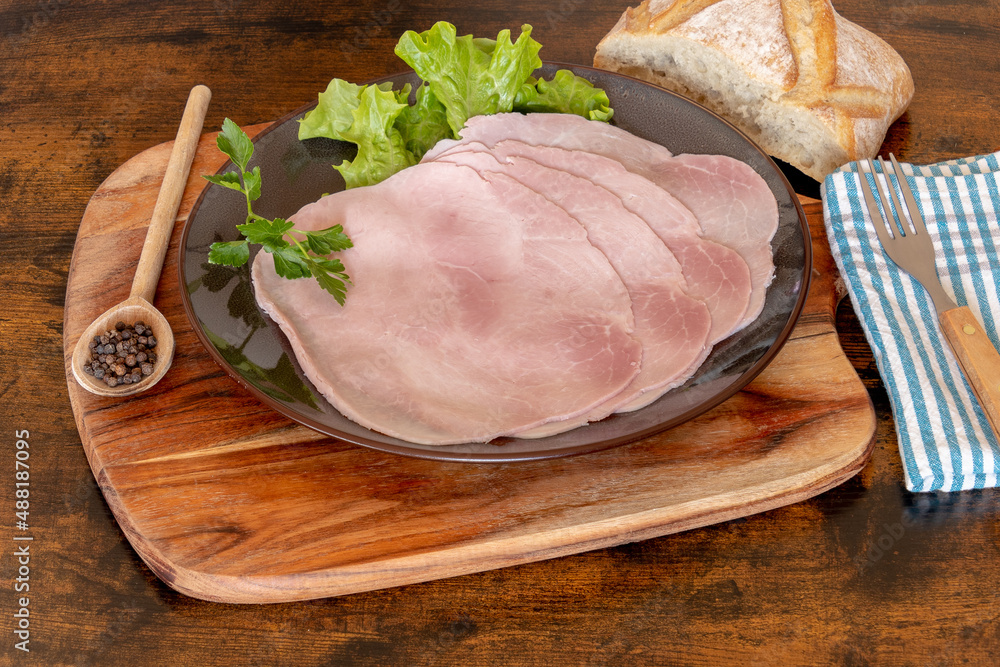 slices of ham in a plate on a wooden board 