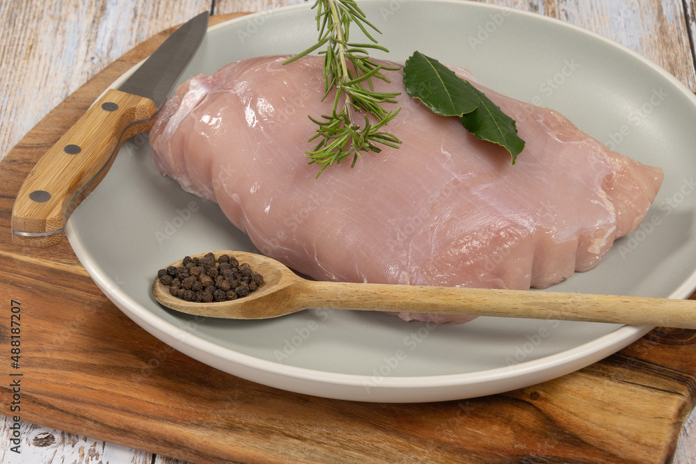 large raw chicken fillet in a dish on a wooden board large raw chicken fillet in a dish on a wooden board