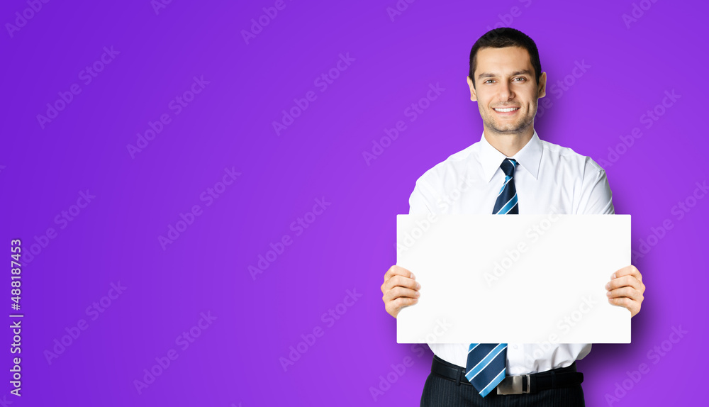 Happy smiling businessman in white shirt and tie, showing blank signboard with copy space area for text, violet purple background. Confident business man holding paper board at studio. Happy smiling businessman in white shirt and tie, showing blank signboard with copy space area for text, violet purple background. Confident business man holding paper board at studio.