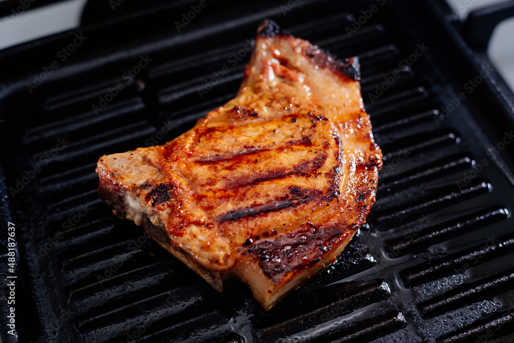 Pork rib steak in sauce and spices fried in a grill pan. The process of cooking pork steak.