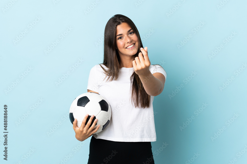 Young football player brazilian girl isolated on blue background making money gesture Young football player brazilian girl isolated on blue background making money gesture