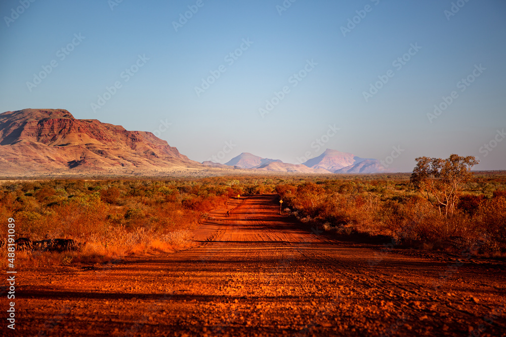 One of the most beautiful red dirt-roads in the Karijini National Park in Western Australia at sunset. - obrazy, fototapety, plakaty 